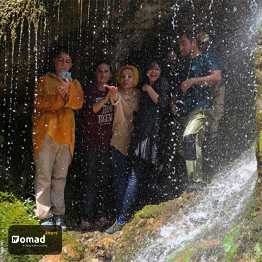 A group of travelers under a waterfall in a nomadic trip