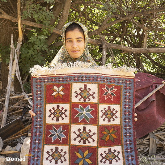 A nomad girl with a nomadic rug in her hand